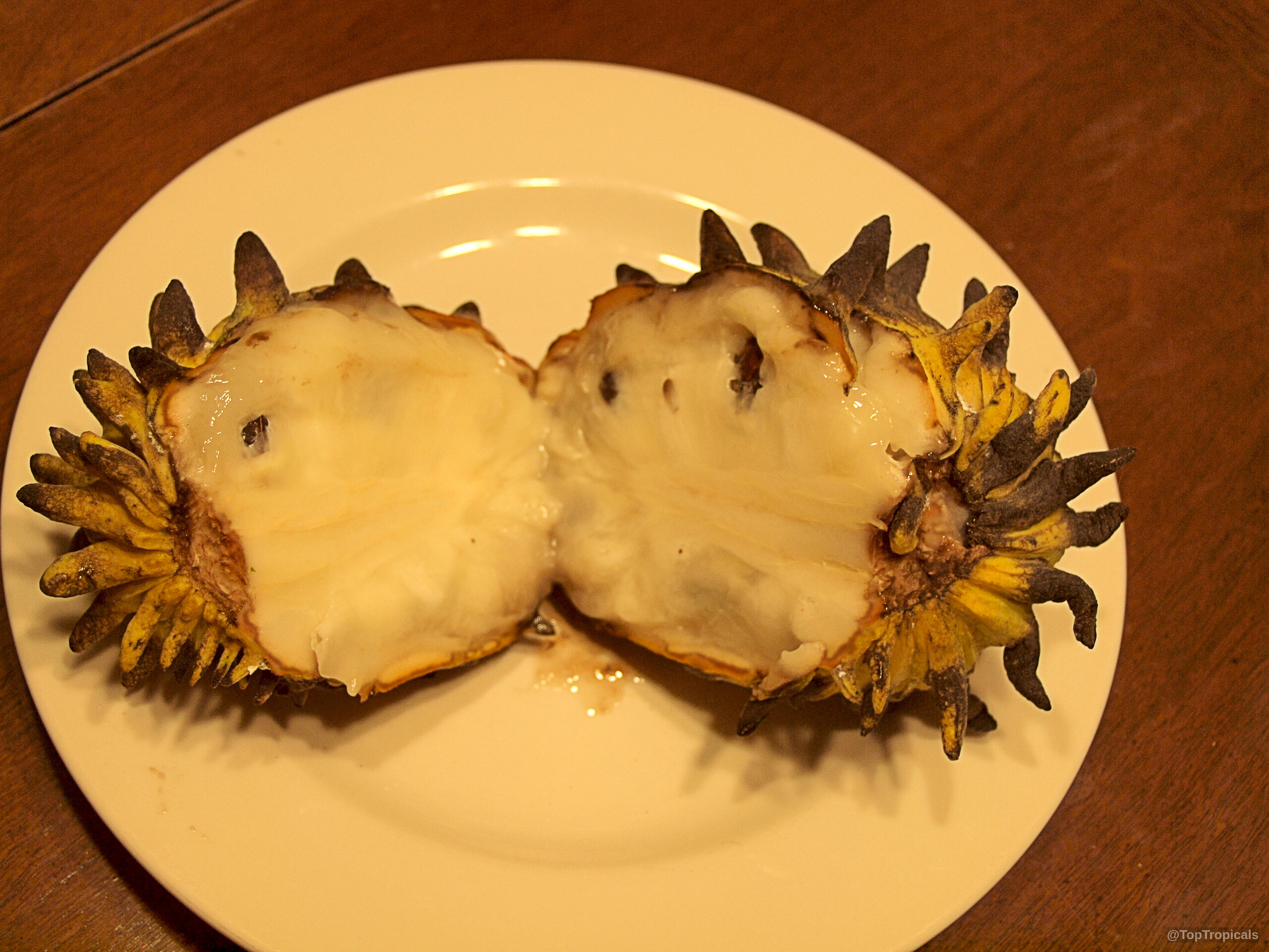 Rollinia deliciosa (Biriba) fruit cut in half with creamy white pulp on a plate. Rollinia deliciosa (Biriba) yellow fruit close up split on a plate.