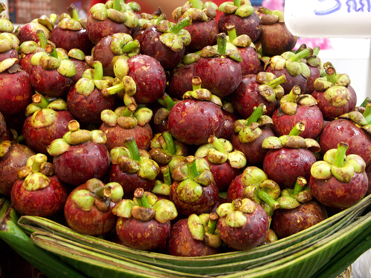 Fresh mangosteen fruit stacked at an Asian market